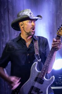 Scotty Meyer music rocks the stage as a man in a cowboy hat plays guitar on Fourth of July.